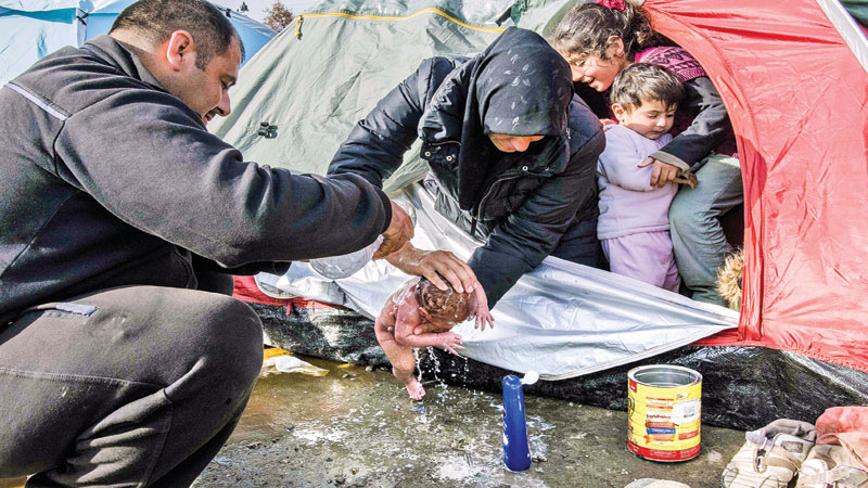 Greece vows refugee transfer as camp baby photo emerges 